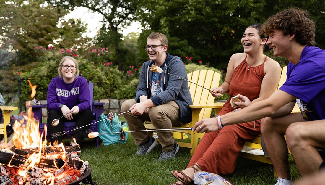 Students roast marshmallows around a fire pit in the fall.